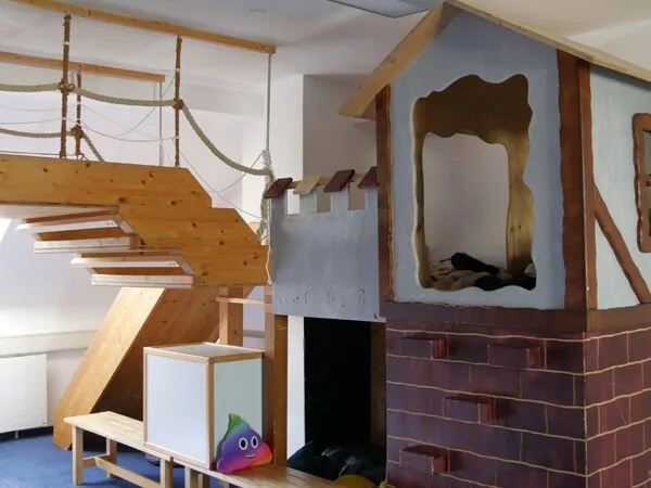 Spielzimmer mit hölzernem Kletterhaus und gemütlichem Rückzugsort